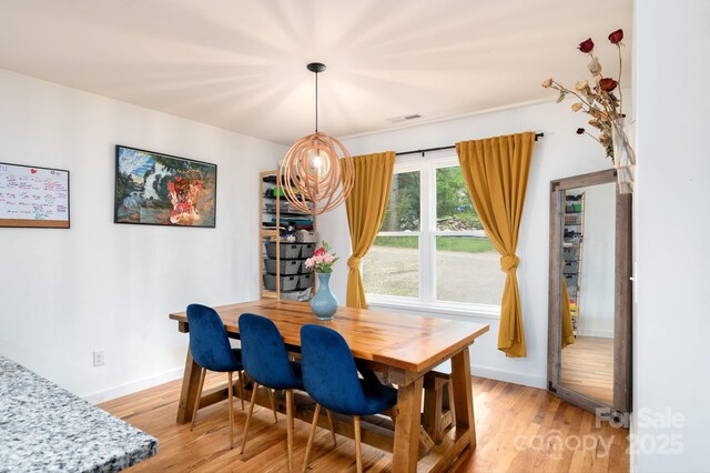 dining area with light wood-style floors, baseboards, and visible vents