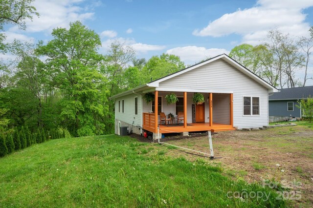 rear view of house featuring covered porch, a yard, and cooling unit