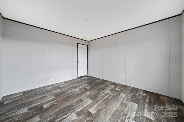 spare room featuring dark wood-type flooring and crown molding
