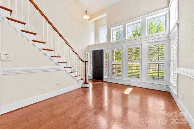 entrance foyer featuring stairs, wood finished floors, and a towering ceiling