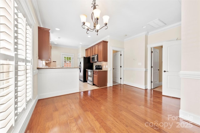 kitchen with brown cabinetry, appliances with stainless steel finishes, light stone counters, light wood finished floors, and a notable chandelier