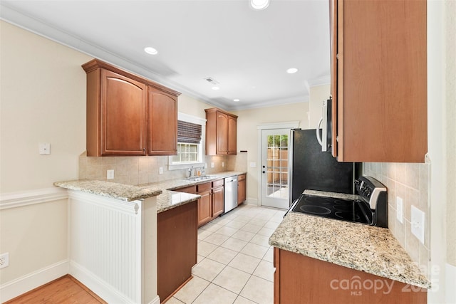kitchen with a peninsula, appliances with stainless steel finishes, decorative backsplash, and a sink