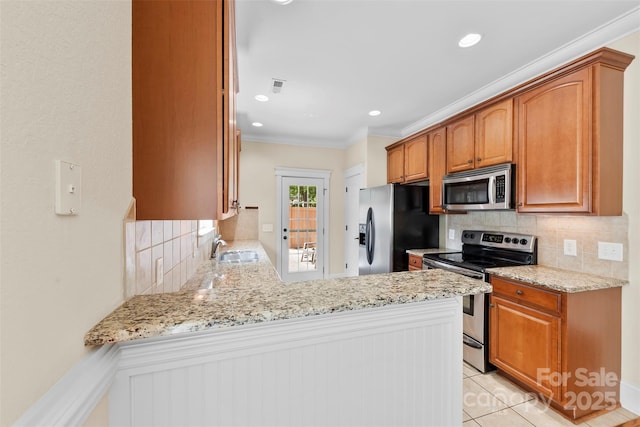 kitchen featuring appliances with stainless steel finishes, light stone counters, a sink, a peninsula, and decorative backsplash
