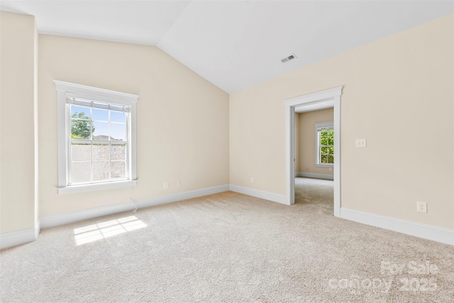 carpeted spare room featuring baseboards, lofted ceiling, and visible vents