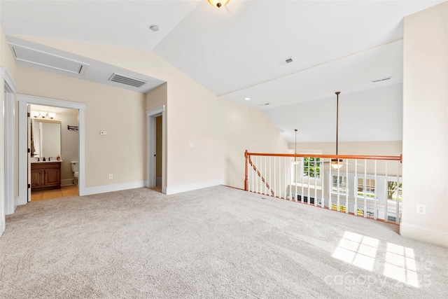 carpeted spare room with baseboards, visible vents, and lofted ceiling