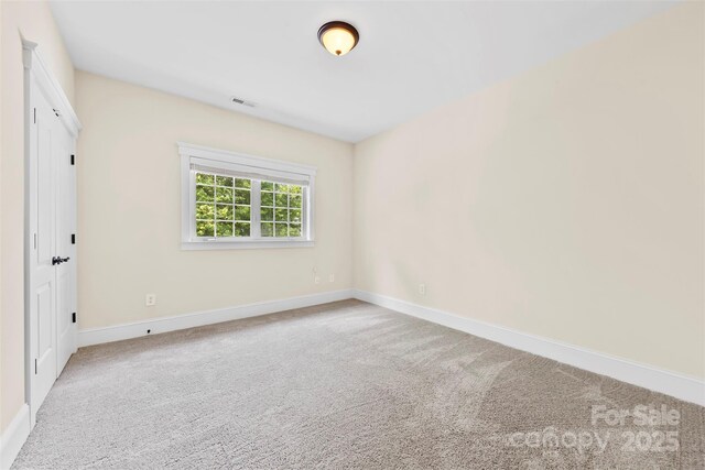 spare room with carpet floors, baseboards, and visible vents