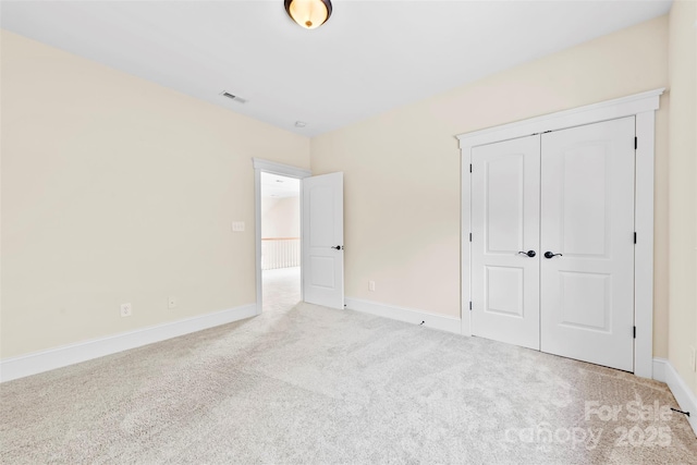 unfurnished bedroom featuring carpet floors, baseboards, visible vents, and a closet