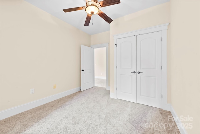 unfurnished bedroom featuring baseboards, ceiling fan, a closet, and light colored carpet