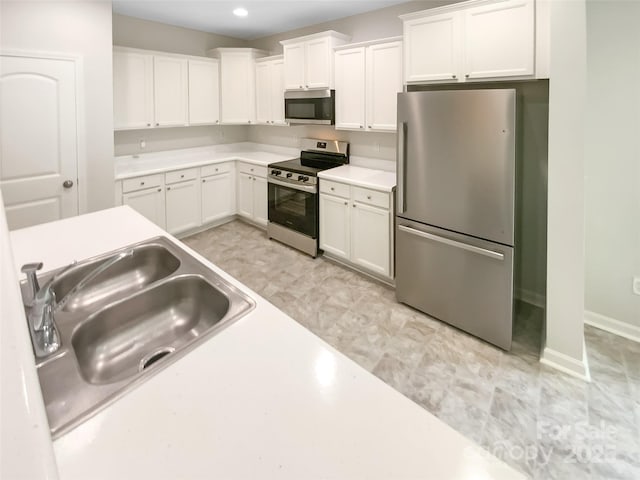 kitchen with recessed lighting, light countertops, white cabinets, a sink, and appliances with stainless steel finishes