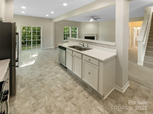 kitchen with ceiling fan, a fireplace, a sink, open floor plan, and stainless steel appliances