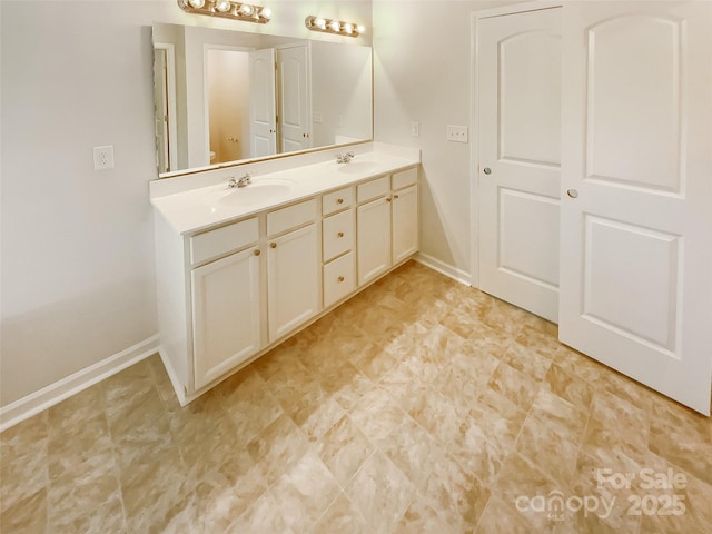 bathroom with double vanity, baseboards, a sink, and tile patterned floors