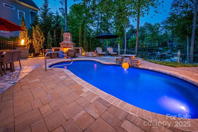 view of swimming pool with an outdoor stone fireplace, a fenced in pool, fence, and a patio area