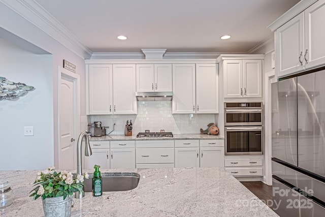 kitchen with white cabinets, under cabinet range hood, appliances with stainless steel finishes, and a sink