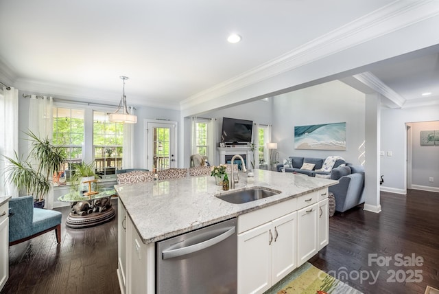 kitchen featuring stainless steel dishwasher, crown molding, open floor plan, light stone counters, and a sink