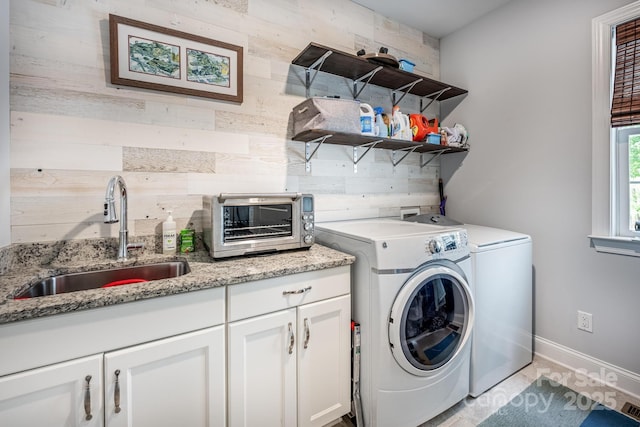 laundry room with independent washer and dryer, wood walls, cabinet space, a sink, and a toaster