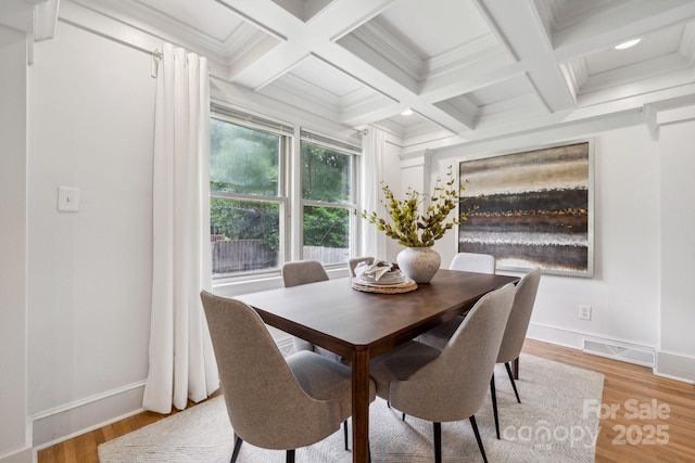 dining area featuring light wood-style floors, beam ceiling, and visible vents