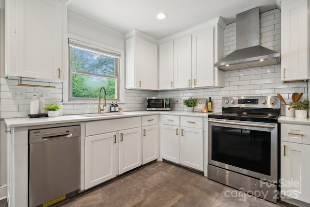 kitchen featuring wall chimney range hood, a sink, light countertops, stainless steel appliances, and tasteful backsplash