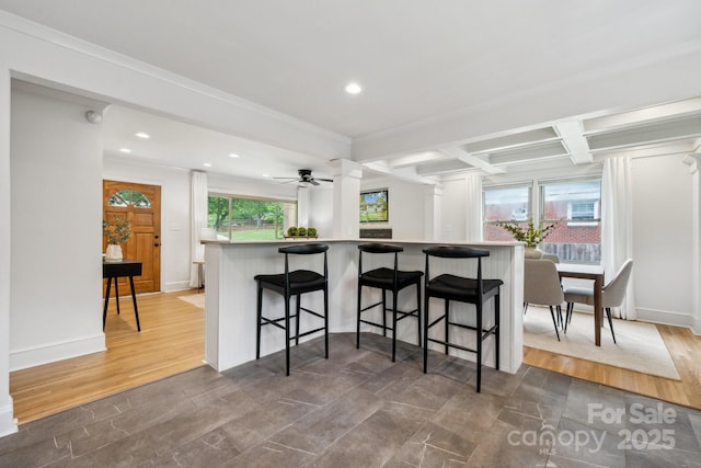 kitchen featuring crown molding, beam ceiling, a breakfast bar area, recessed lighting, and coffered ceiling