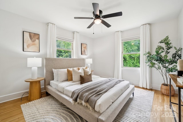 bedroom featuring a ceiling fan, baseboards, and light wood-style flooring