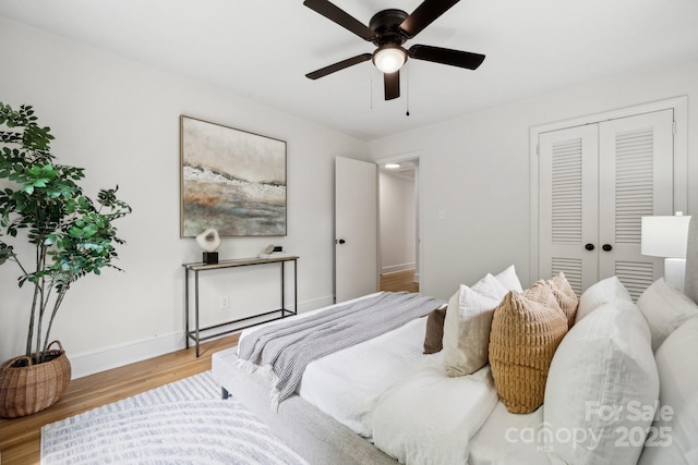 bedroom with baseboards, a ceiling fan, a closet, and wood finished floors