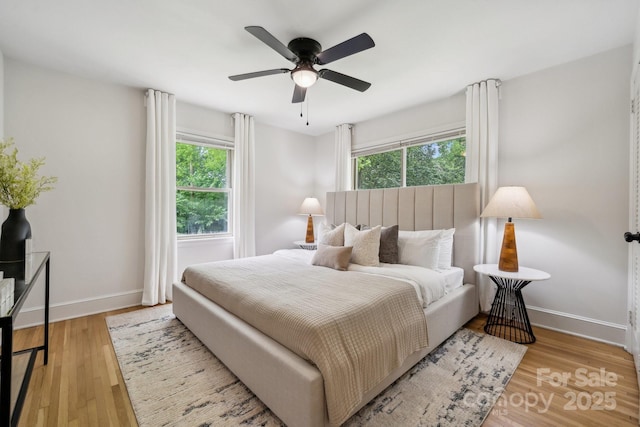 bedroom featuring baseboards, multiple windows, and wood finished floors