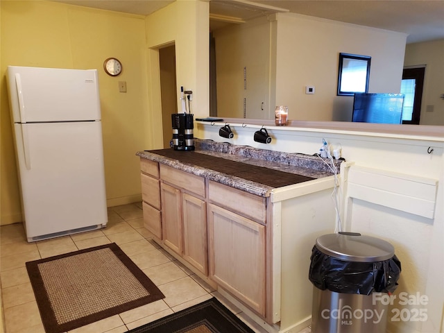 kitchen with light tile patterned floors, dark countertops, and freestanding refrigerator