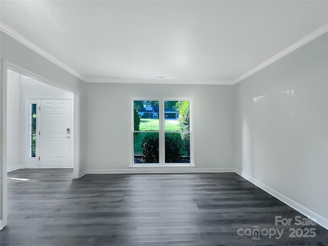spare room with crown molding, baseboards, and dark wood-style floors