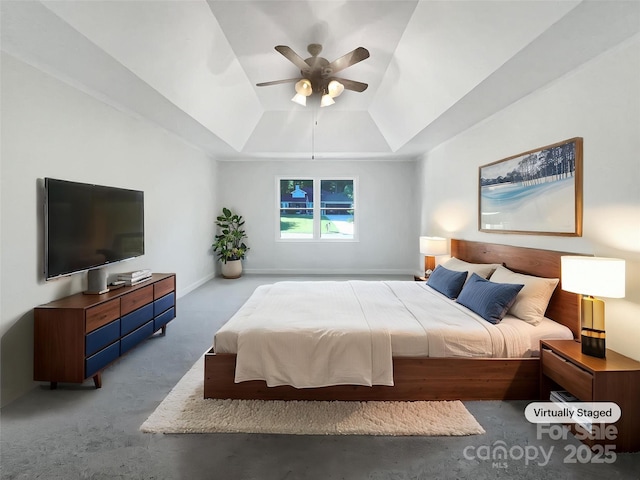 bedroom featuring carpet floors, a raised ceiling, ceiling fan, and baseboards