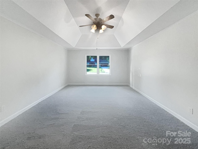 carpeted empty room featuring baseboards, ceiling fan, and a tray ceiling