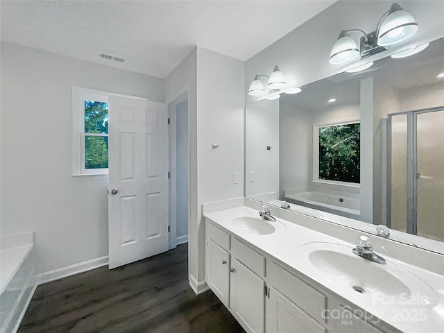 bathroom with a sink, a bath, wood finished floors, and visible vents