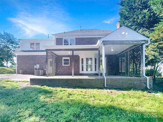rear view of house featuring a patio, a yard, central AC, and brick siding