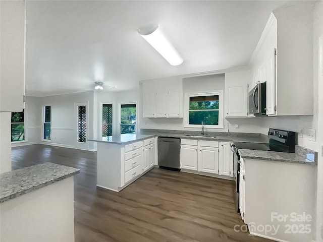 kitchen with a sink, stainless steel appliances, white cabinetry, a peninsula, and dark wood-style floors