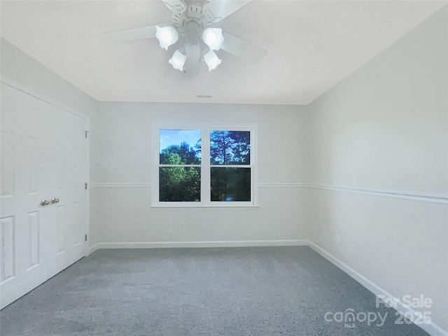 carpeted spare room featuring baseboards, a ceiling fan, and visible vents