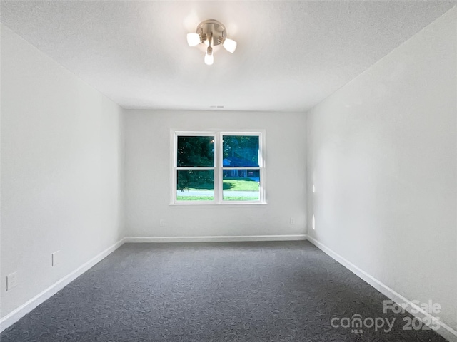 empty room featuring baseboards and dark carpet