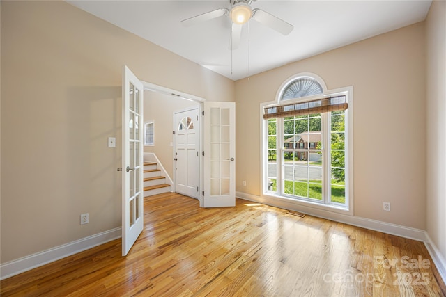 empty room featuring french doors, light wood finished floors, baseboards, and ceiling fan