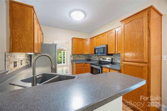 kitchen with stainless steel appliances, tasteful backsplash, a sink, and dark countertops