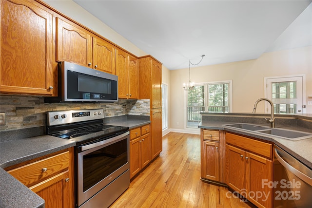 kitchen with appliances with stainless steel finishes, a sink, dark countertops, a chandelier, and vaulted ceiling
