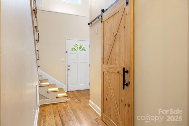 entrance foyer featuring a barn door, wood finished floors, baseboards, and stairs