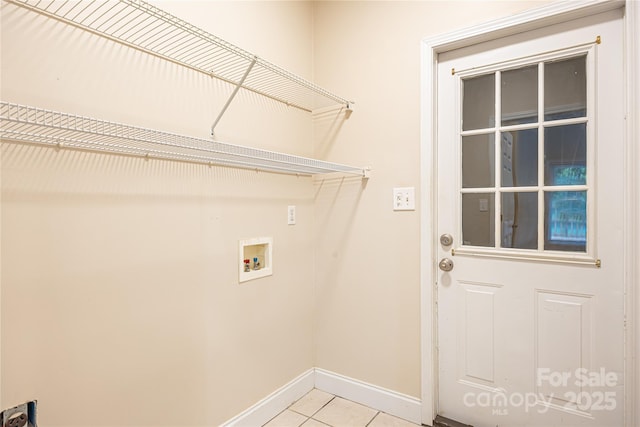 clothes washing area with light tile patterned floors, washer hookup, and baseboards