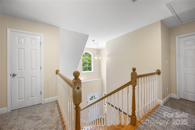 hallway with an upstairs landing, attic access, and baseboards