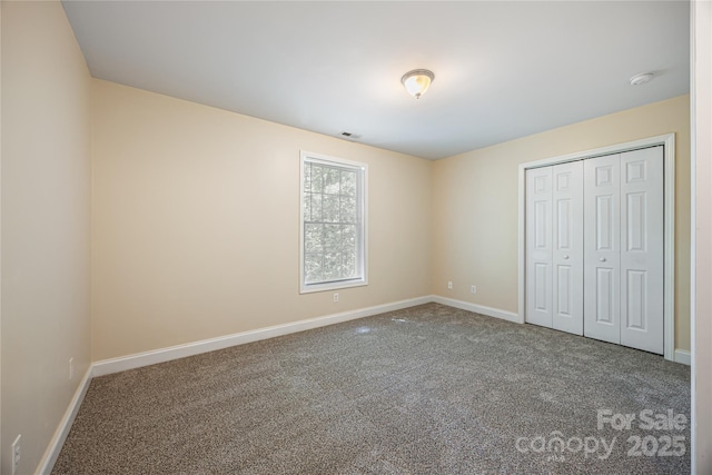 unfurnished bedroom featuring baseboards, carpet floors, and a closet
