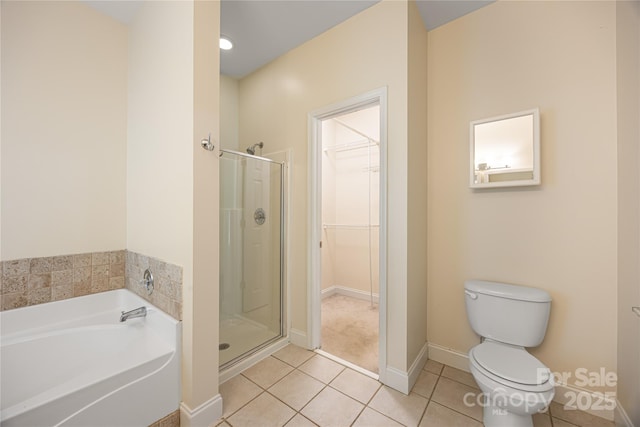 bathroom featuring tile patterned floors, a stall shower, toilet, a bath, and a spacious closet