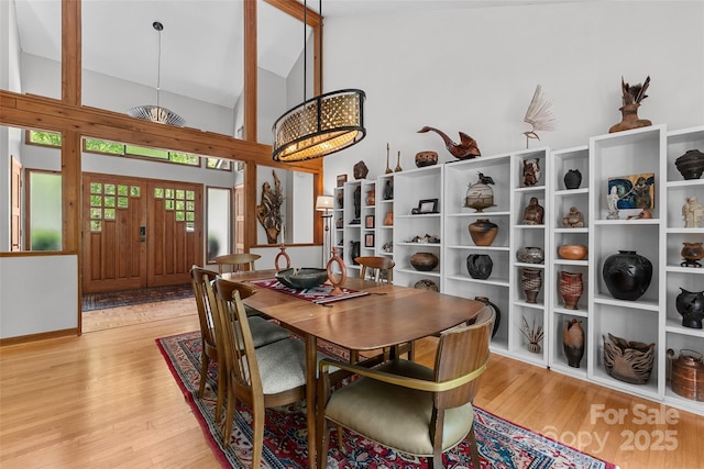 dining area with high vaulted ceiling and wood finished floors