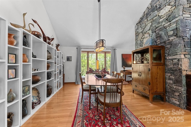 dining area with vaulted ceiling and light wood finished floors