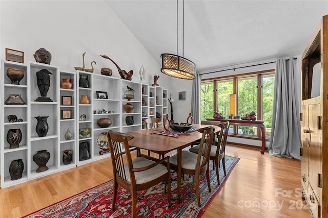 dining room with a textured ceiling, light wood-style flooring, and lofted ceiling