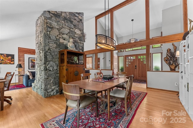 dining room with high vaulted ceiling, baseboards, and wood finished floors