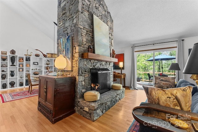 sitting room featuring a textured ceiling, light wood-style flooring, lofted ceiling, and a fireplace