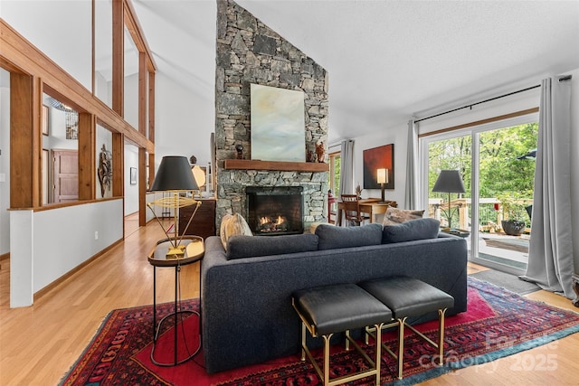 living room featuring wood finished floors, lofted ceiling, and a stone fireplace