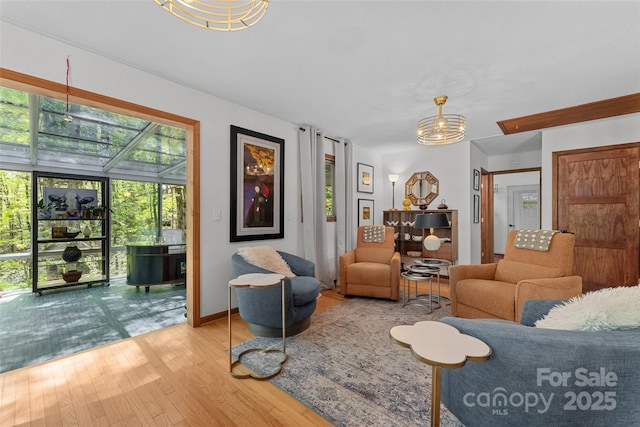 living room with baseboards, hardwood / wood-style floors, and an inviting chandelier