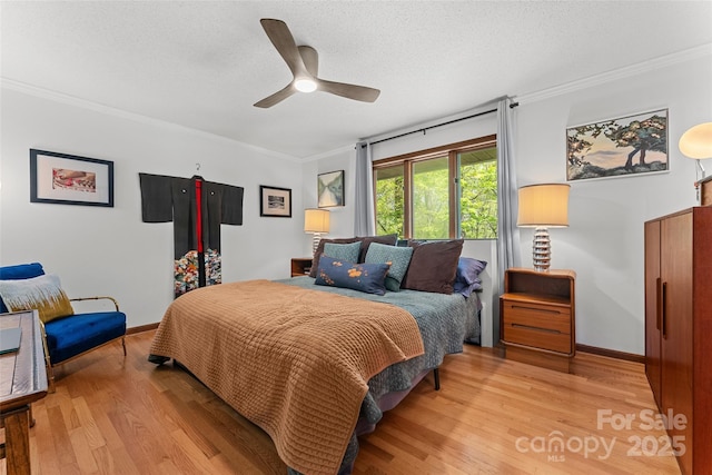 bedroom featuring baseboards, ornamental molding, light wood finished floors, and ceiling fan